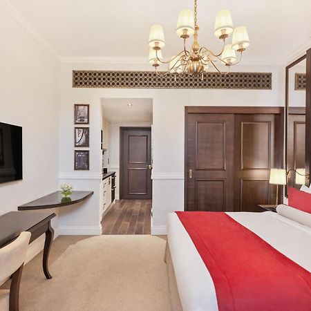 Dukes The Palm, A Royal Hideaway Hotel Dubai Exterior foto The photo shows a well-decorated hotel room. It features a large bed with a red and white color scheme, complemented by stylish pillows and a tufted headboard. A modern chandelier hangs from the ceiling, providing light. There is a flat-screen TV mou