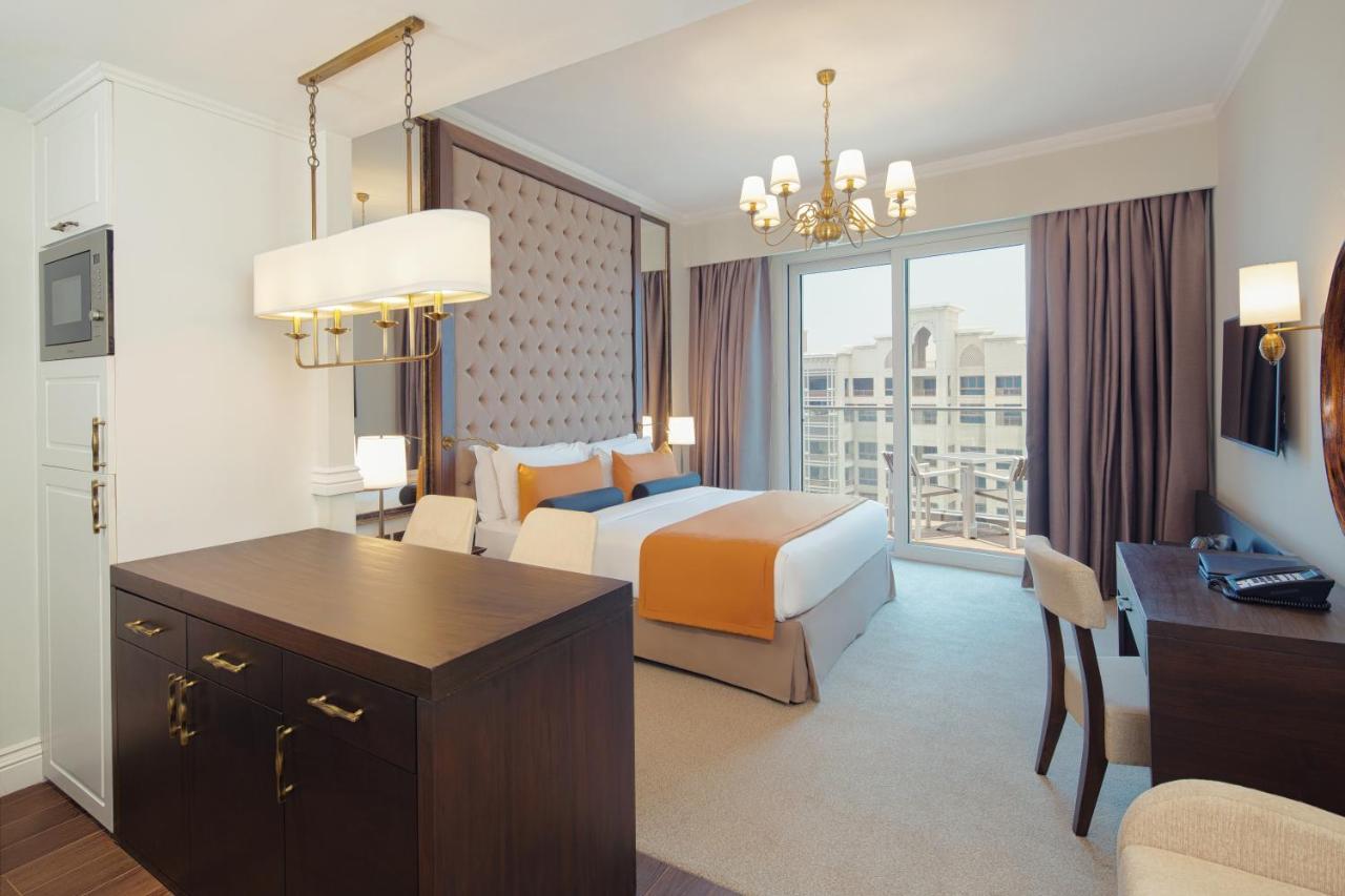 Dukes The Palm, A Royal Hideaway Hotel Dubai Exterior foto The photo shows a modern hotel room with a stylish design. The room features a large bed with orange and white bedding, complemented by a decorative headboard. There are two curtains framing a large window that allows natural light to fill the space.
