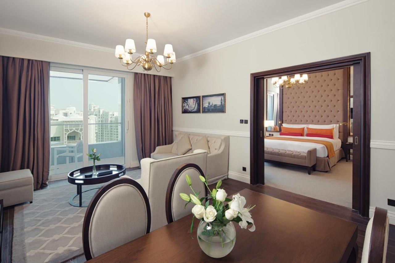 Dukes The Palm, A Royal Hideaway Hotel Dubai Exterior foto The photo depicts a well-furnished hotel suite or living space. In the foreground, there is a dining table with plush chairs and a vase of flowers. Beyond that, you can see a cozy living area with a sofa set and a coffee table, illuminated by a chand
