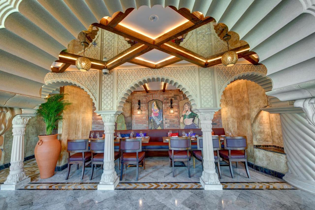 Dukes The Palm, A Royal Hideaway Hotel Dubai Exterior foto The photo showcases the interior design of a restaurant, characterized by a beautiful architectural style. There is an ornate archway supported by pillars, which adds a classical touch. The ceiling features a unique, layered design, creating an elega