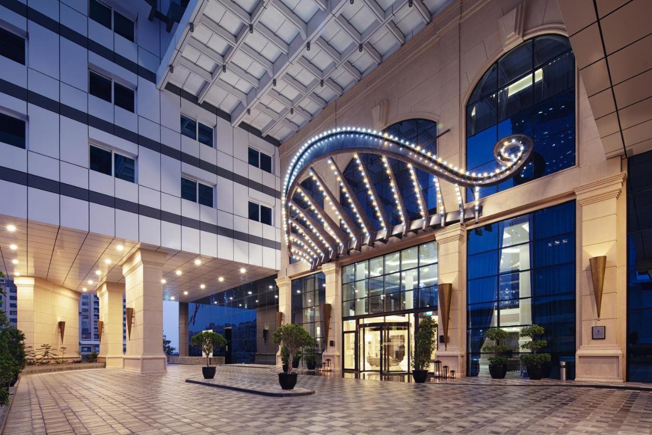 Dukes The Palm, A Royal Hideaway Hotel Dubai Exterior foto The photo shows the entrance of a modern building, likely a hotel or a prestigious office space. The facade features a prominent archway adorned with lights, creating an inviting and elegant atmosphere. The entrance has large glass doors, and there a