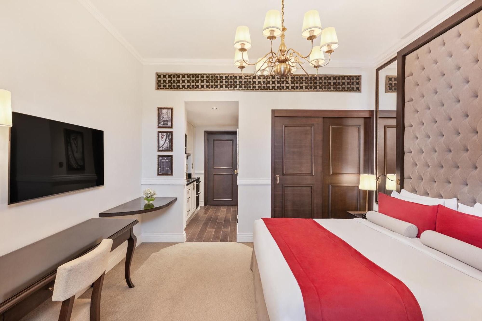 Dukes The Palm, A Royal Hideaway Hotel Dubai Exterior foto The photo shows a well-decorated hotel room. It features a large bed with a red and white color scheme, complemented by stylish pillows and a tufted headboard. A modern chandelier hangs from the ceiling, providing light. There is a flat-screen TV mou