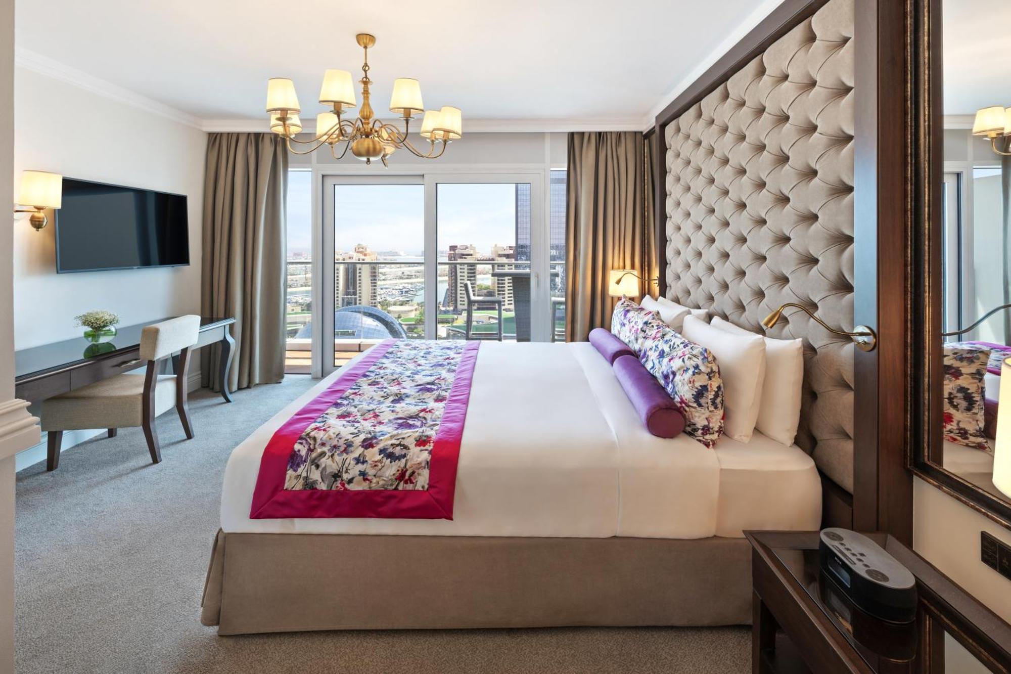 Dukes The Palm, A Royal Hideaway Hotel Dubai Exterior foto The photo depicts a luxurious hotel room. The prominent features include:

- A large bed with a tufted headboard, adorned with decorative pillows and a colorful bed runner.
- A spacious layout that includes a chic chandelier hanging from the ceiling.