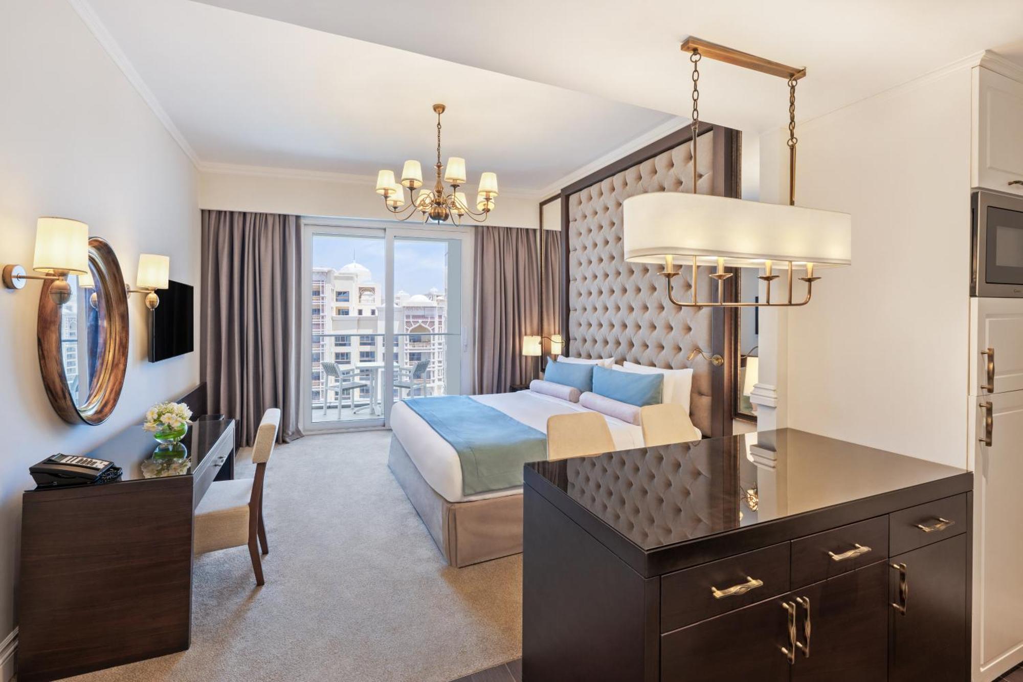 Dukes The Palm, A Royal Hideaway Hotel Dubai Exterior foto The photo shows a luxurious hotel room featuring modern decor. The room includes a large bed with a tufted headboard, soft bedding in light colors, and stylish furnishings. There is a desk and a chair in one corner, along with a decorative mirror and