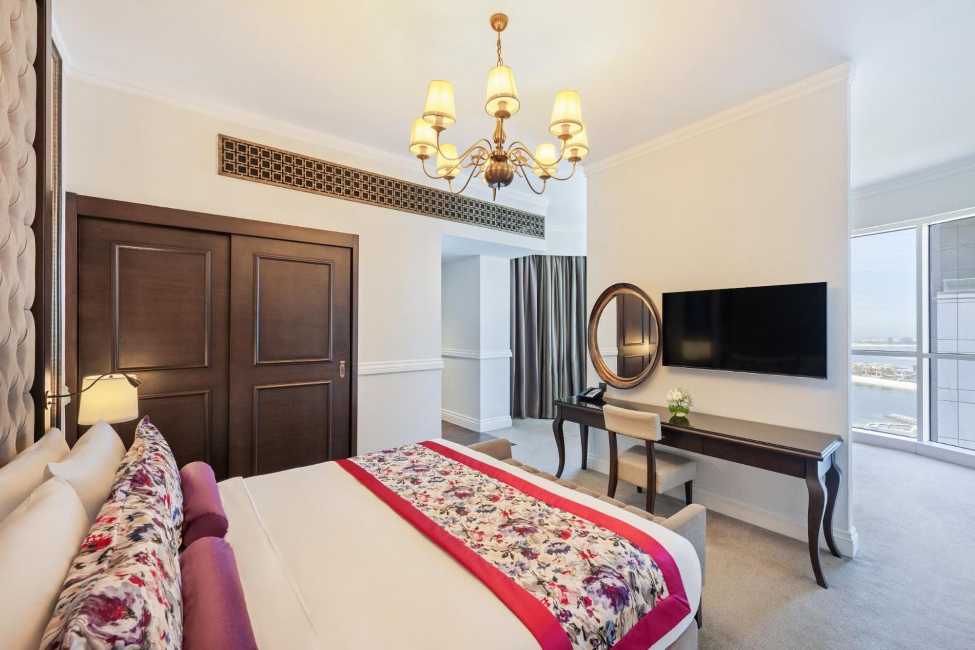 Dukes The Palm, A Royal Hideaway Hotel Dubai Exterior foto The photo shows an elegantly furnished bedroom. The room features a large bed with decorative pillows and a vibrant bedspread. There's a stylish chandelier hanging from the ceiling, adding a touch of sophistication. To one side, there are double door