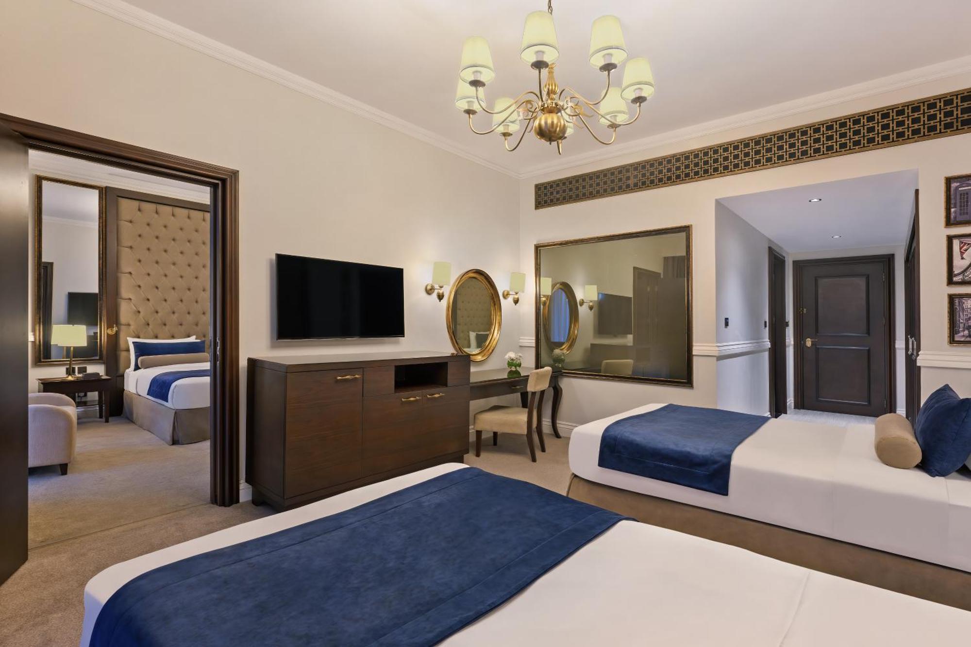 Dukes The Palm, A Royal Hideaway Hotel Dubai Exterior foto The photo shows a hotel room featuring two beds with blue and white bedding. There’s a light-colored carpet on the floor. A chandelier hangs from the ceiling, providing illumination. A wooden dresser is positioned against one wall, with a flat-screen