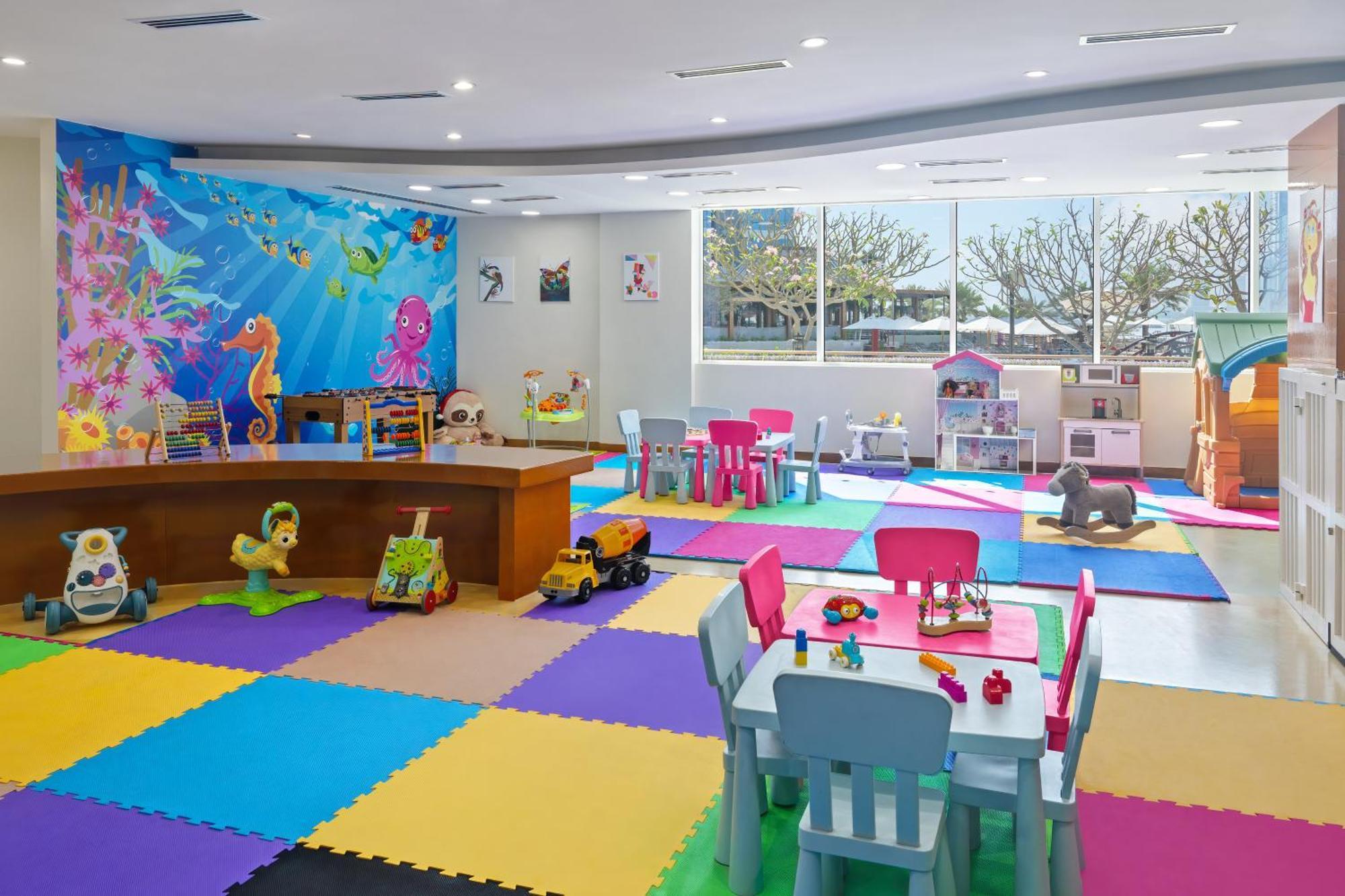 Dukes The Palm, A Royal Hideaway Hotel Dubai Exterior foto The photo shows a bright and colorful children's playroom. The floor is covered with interlocking foam mats in various colors, including blue, green, yellow, and purple. There is a large table made of wood at the center, surrounded by colorful chairs