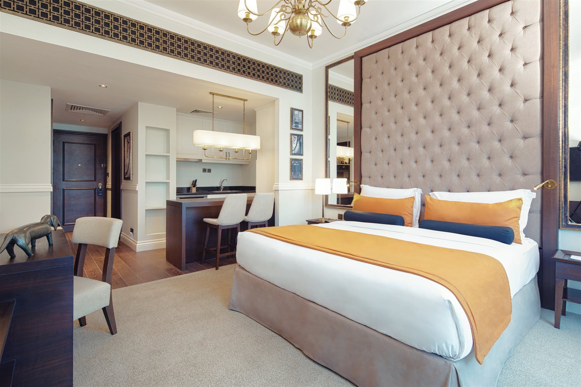 Dukes The Palm, A Royal Hideaway Hotel Dubai Exterior foto The image shows a modern hotel room featuring a stylish design. In the center, there's a large bed with a tufted headboard upholstered in light brown, complemented by two decorative pillows in blue and orange. The room has a neutral color scheme with